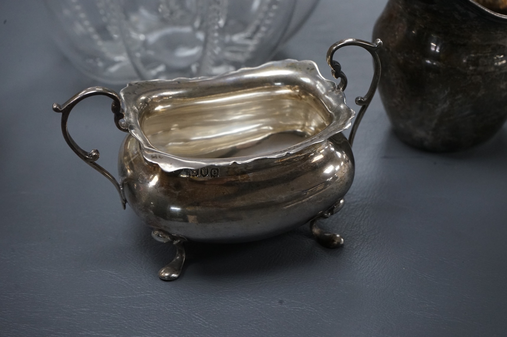A late Victorian silver mounted lobed glass biscuit barrel by Hukin & Heath, with patent handle, London, 1899, height 14.4cm excluding the handle, together with a silver two handled condiment, a silver sugar bowl and a s